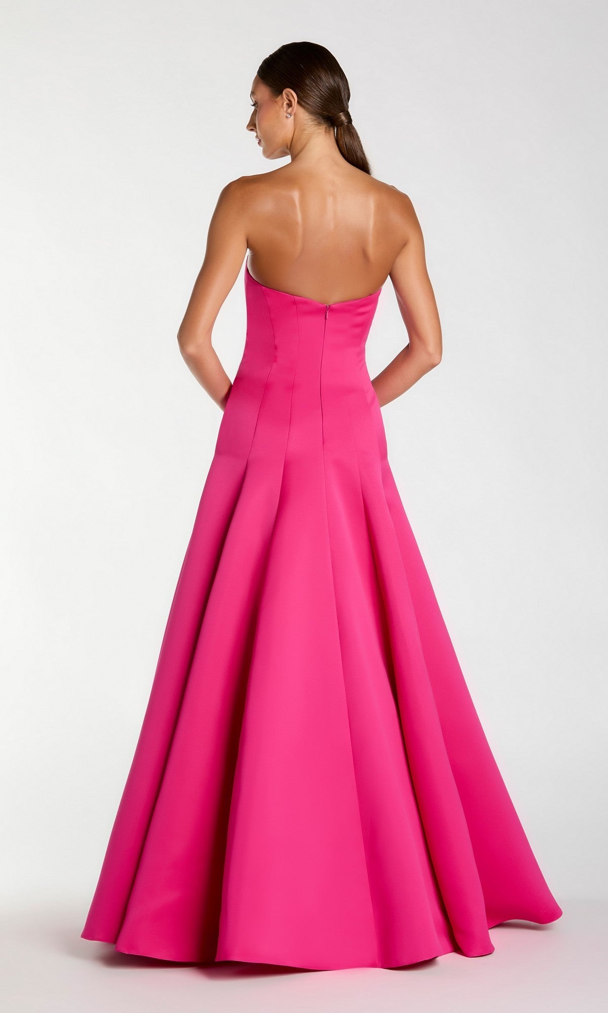 A woman stands facing away, wearing the Long Formal Dress: Mac Duggal 2357—a strapless, floor-length pink ballgown with a flared skirt.